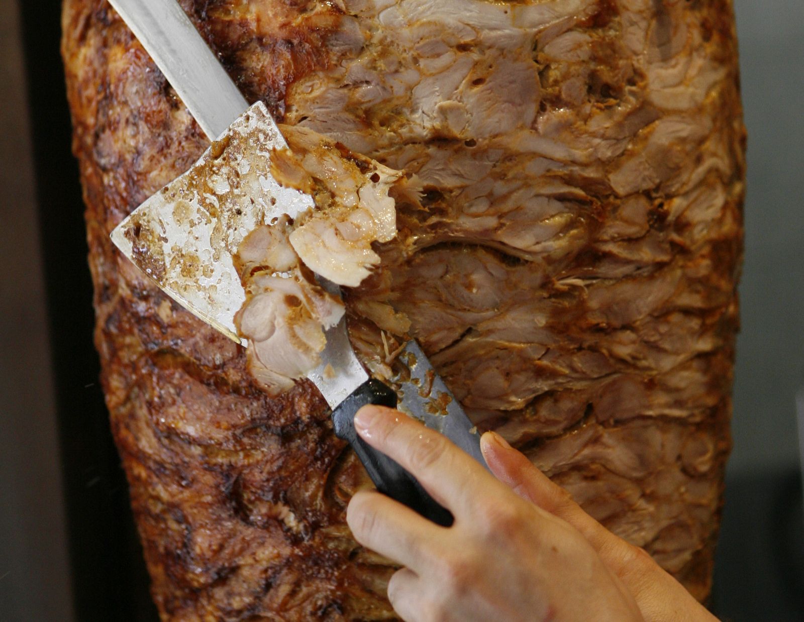Un trabajador corta una tira de kebab en un restaurante de Dortmund, Alemania.