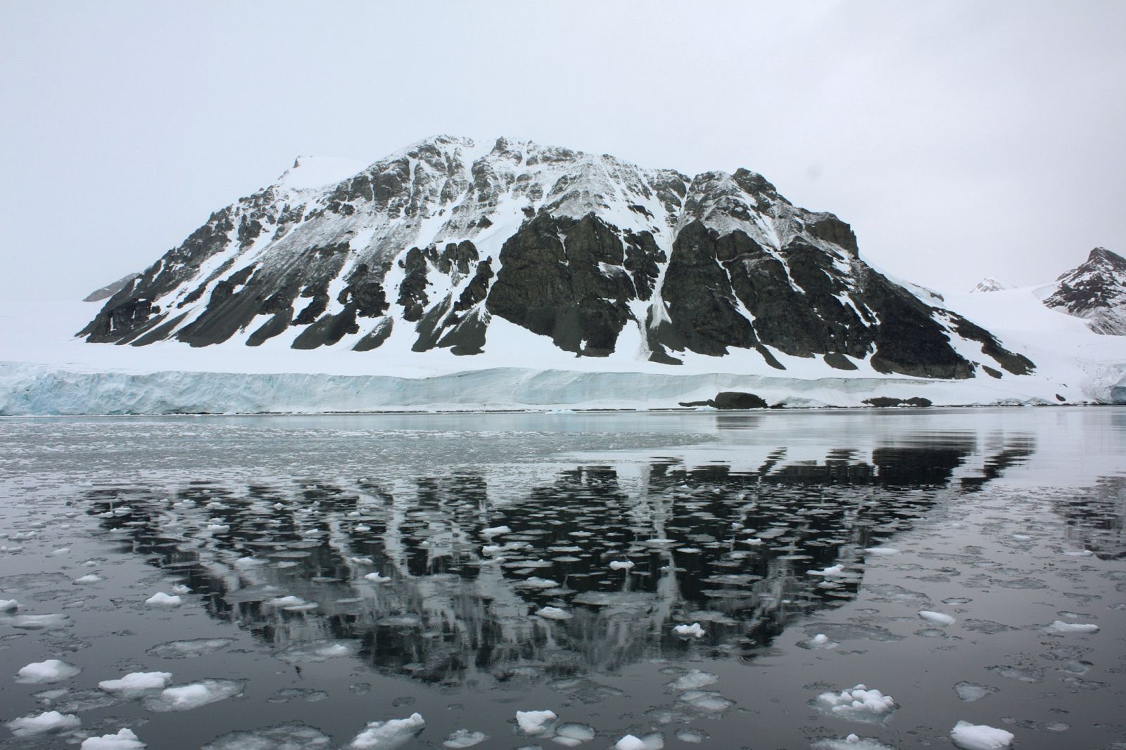 Una montaña se refleja en una bahía que antes estaba cubierta por el glacias Sheldon, en la Antártida.