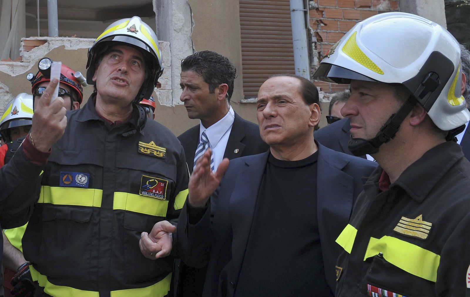 Los bomberos explican a Berlusconi sus operaciones de rescate.