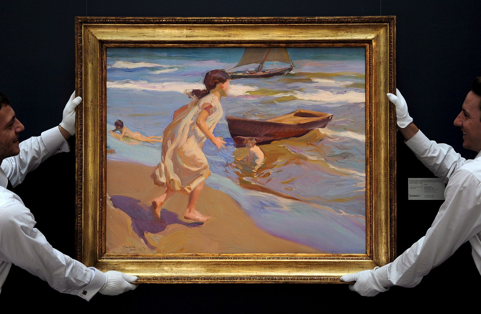 Unos empleados de la casa de susbastas Sotheby's cuelgan el cuadro 'Niña entrando en el baño, del pintor español Joaquín Sorolla.