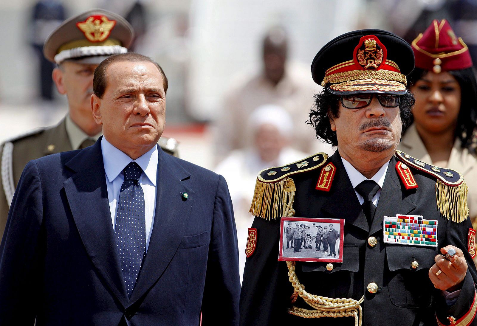 Cuando ha bajado del avión, en donde le estaba esperando Berlusconi, Gadafi llevaba colgada en la chaqueta una foto del líder de la resistencia libia anti-italiana.