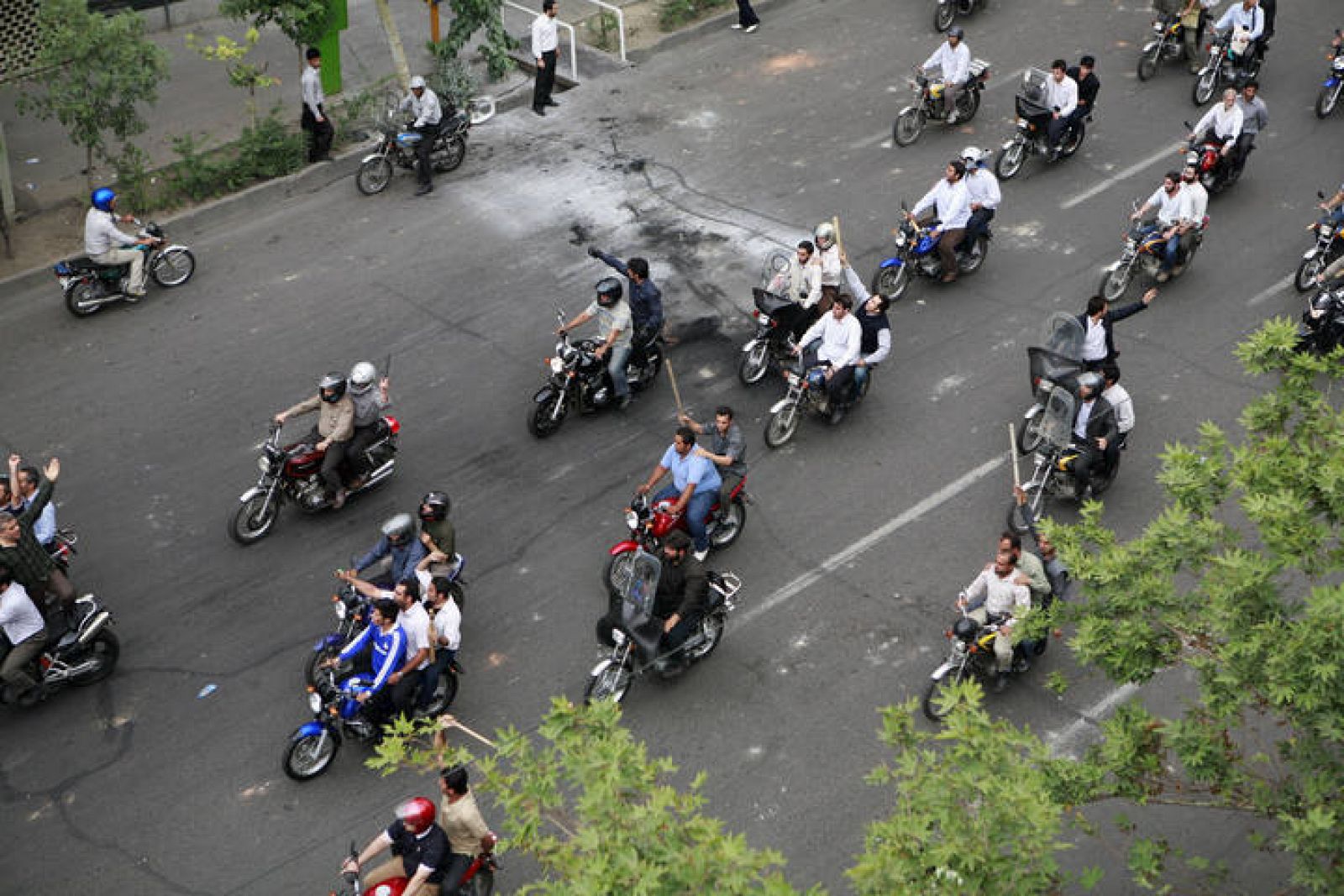 Grupos de manifestantes iraníes armados con palos recorren en moto el centro de Teherán.