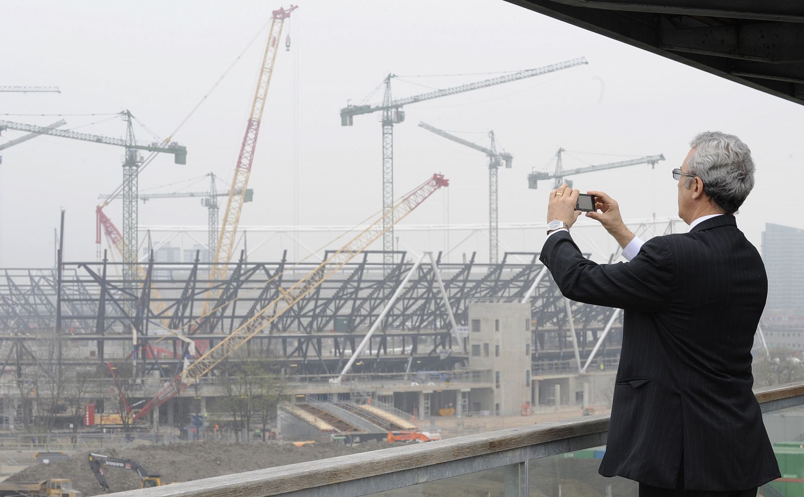 A man photographs the main Olympic Stadium construction at Stratford in east London