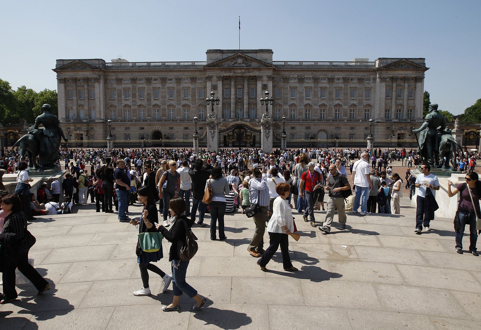 Tourists stand in front of Buckingham Palace in London