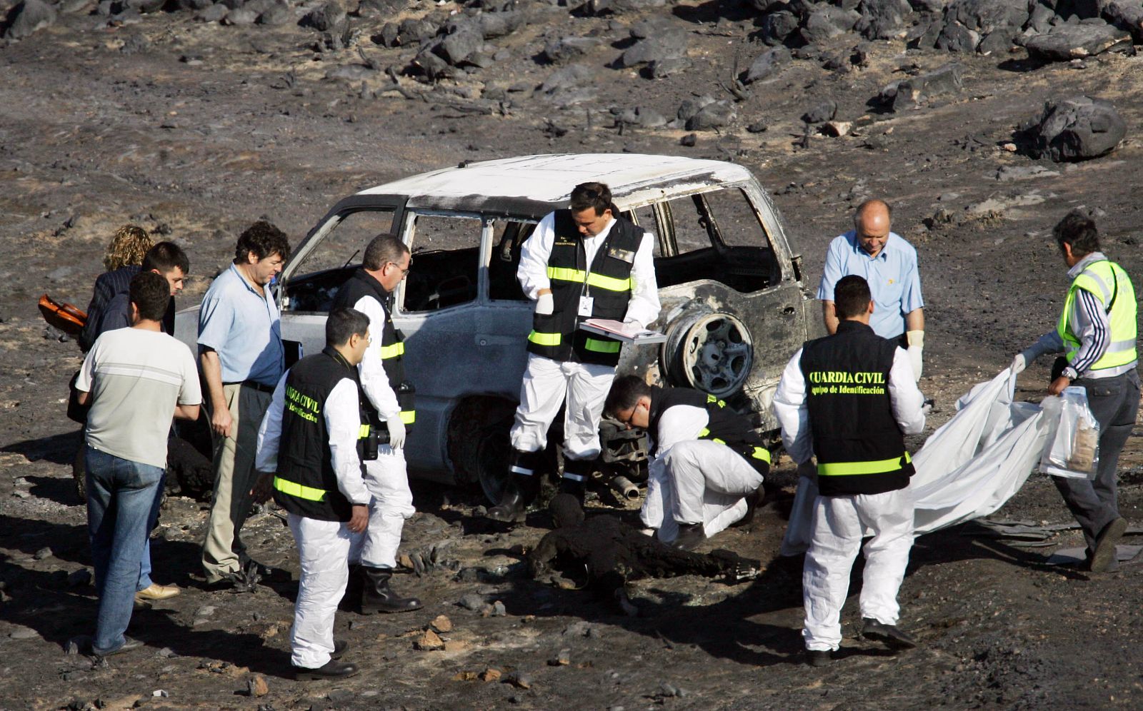 Forensics inspect the blackened corpse of a fire-fighter after deadly forest fire in central Spain.