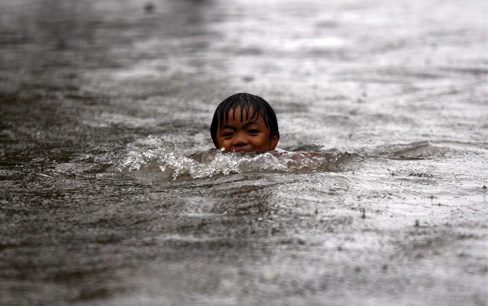 Un niño nada en por las calles inundadas de la localidad de Victoria, en la provincia de Laguna al sur de Manila