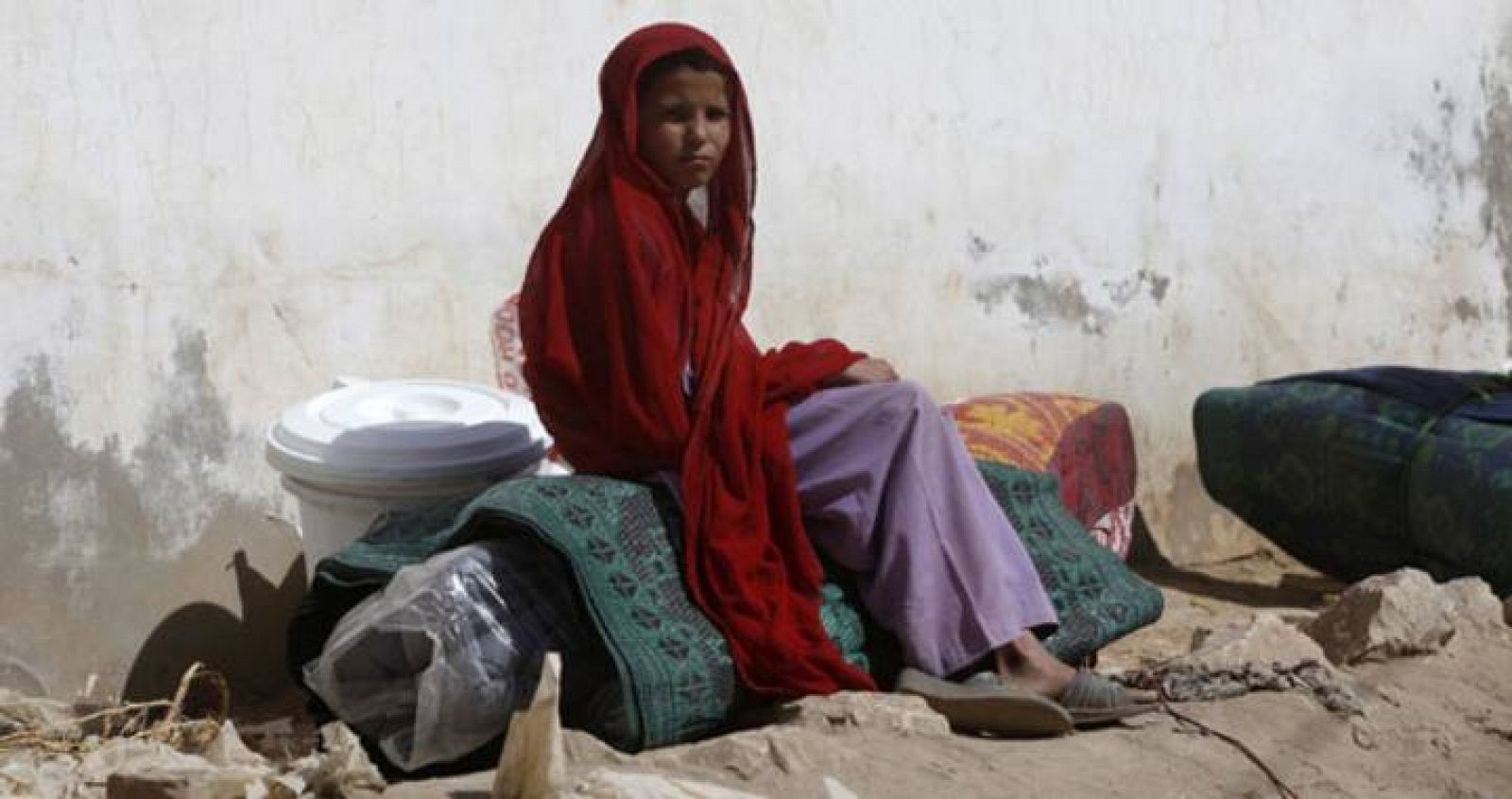 A girl, fleeing a military offensive in South Waziristan, sits on her family's belongings in Dera Ismail Khan