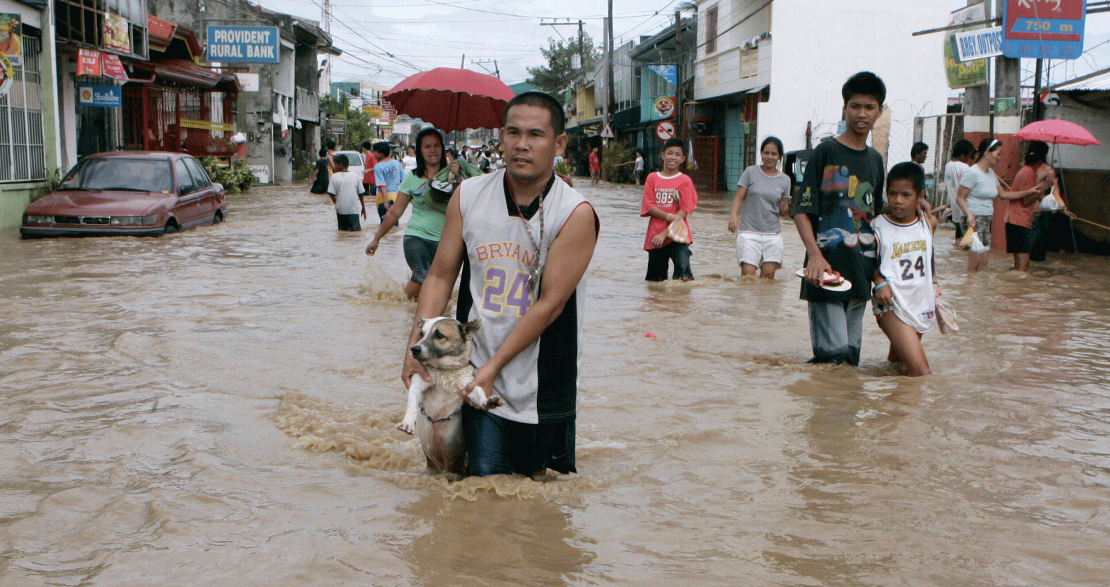 Un hombres sostiene a su perro mientras en mitad de una calle anegada por las inundaciones del tifón "Marinae" en la provincia filipina de Laguna.