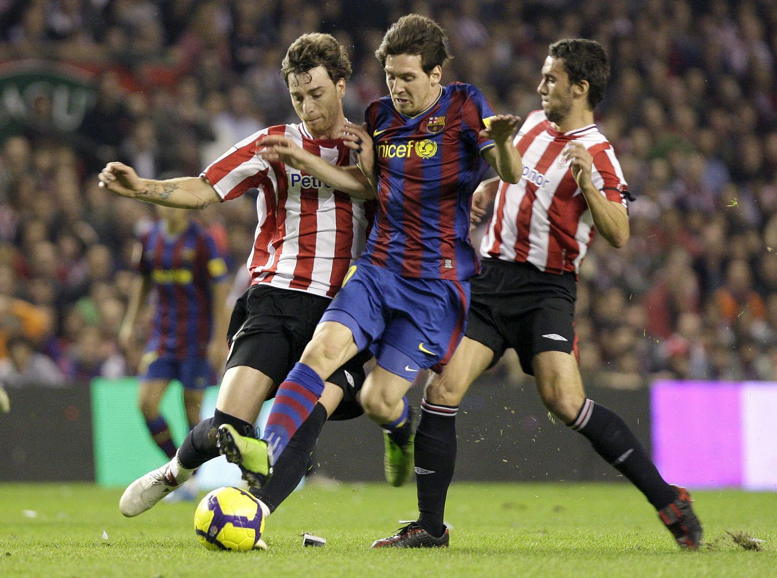 Los defensas del Athlétic de Bilbao, Fernando Amorebieta y Ustaritz Aldekoaotalora, intentan parar al delantero argentino del F.C. Barcelona, Lionel Messi.