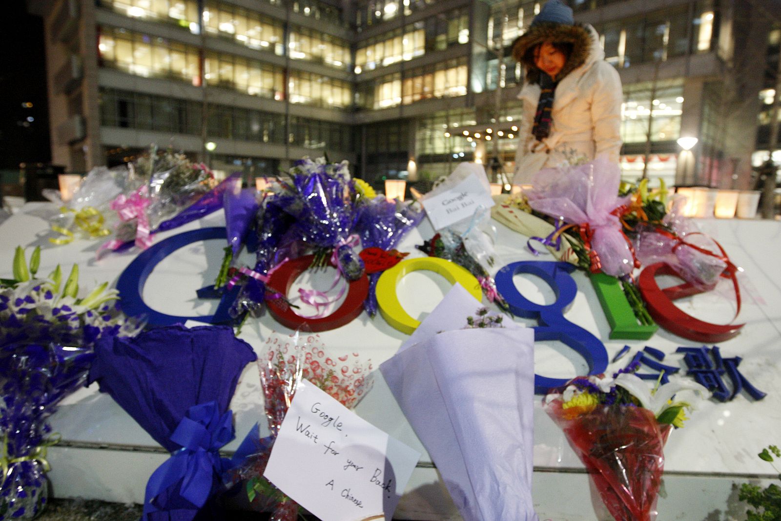 Una mujer lee los mensajes dejados junto a los ramos de flores en la sede de Google en Pekín, tras la amenaza de la compañía de abandonar el país por la censura.