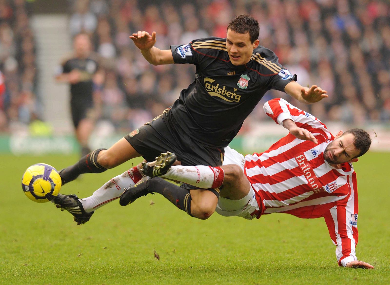 El suizo Philipp Degen del Liverpool FC, (i), lucha por el control del balón con Danny Higginbotham del Stoke