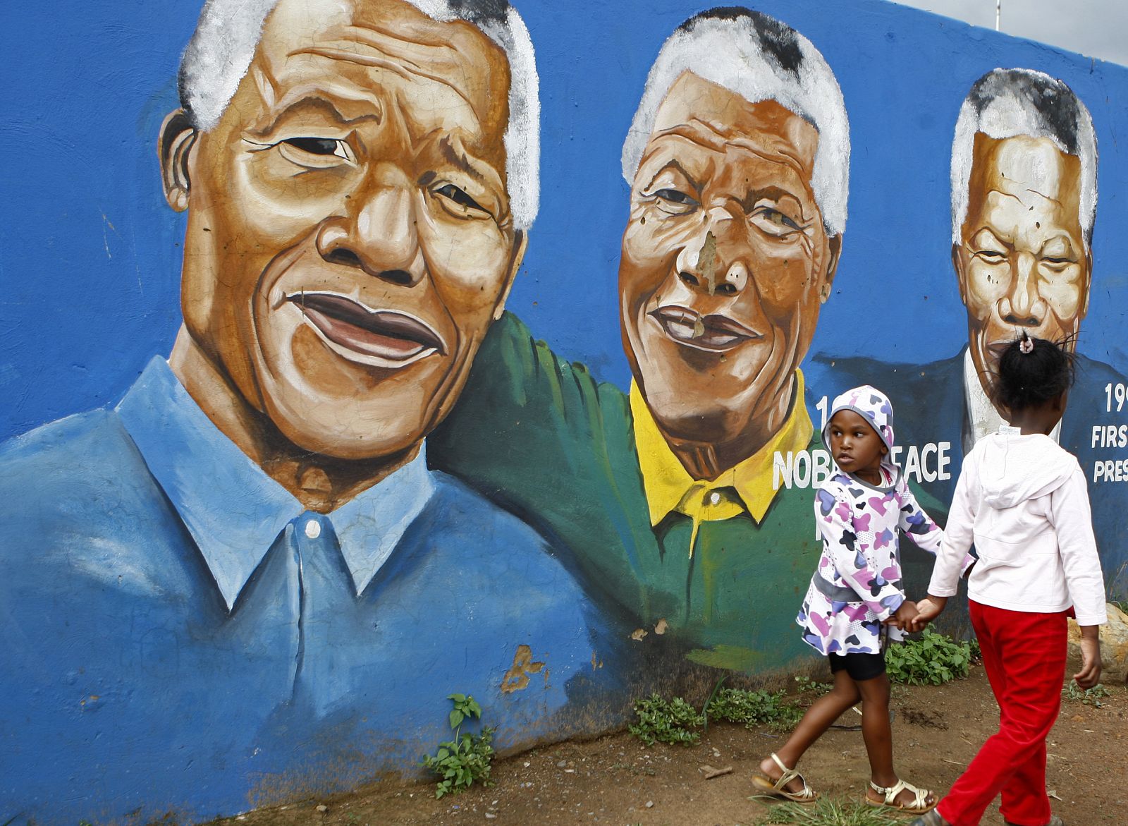 Dos niñas pasean junto a un grafiti del ex presidente de Sudáfrica Nelson Mandela en Soweto.