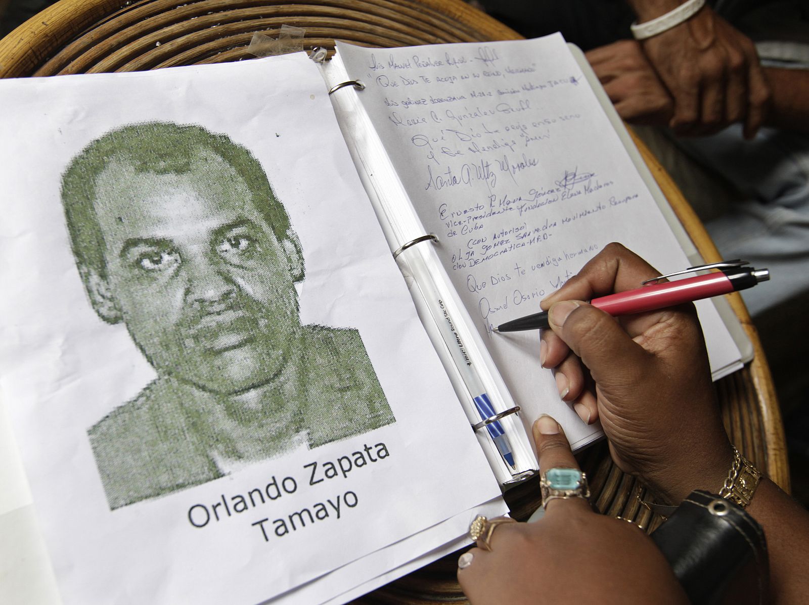 Una mujer firma en el libro de condolencias de Orlando Zapata.