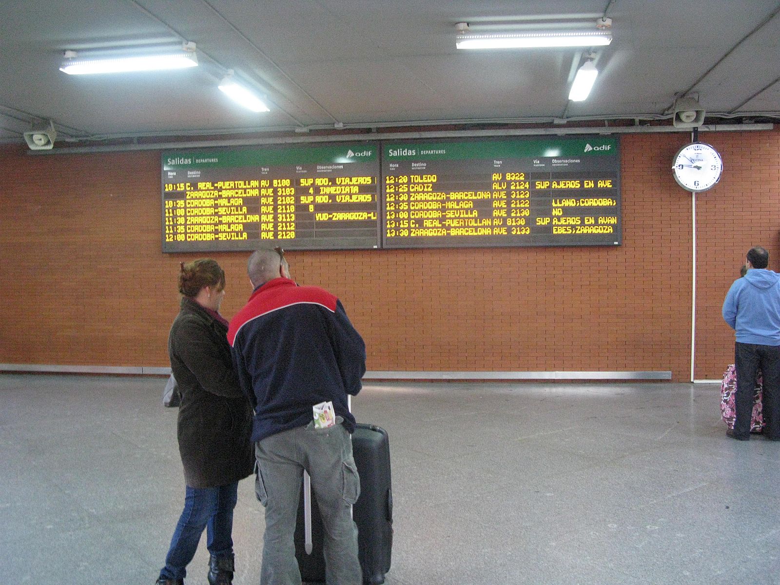 Javier y Mar comprueban en el panel de información de Atocha si su tren a Málaga está afectado por la huelga.