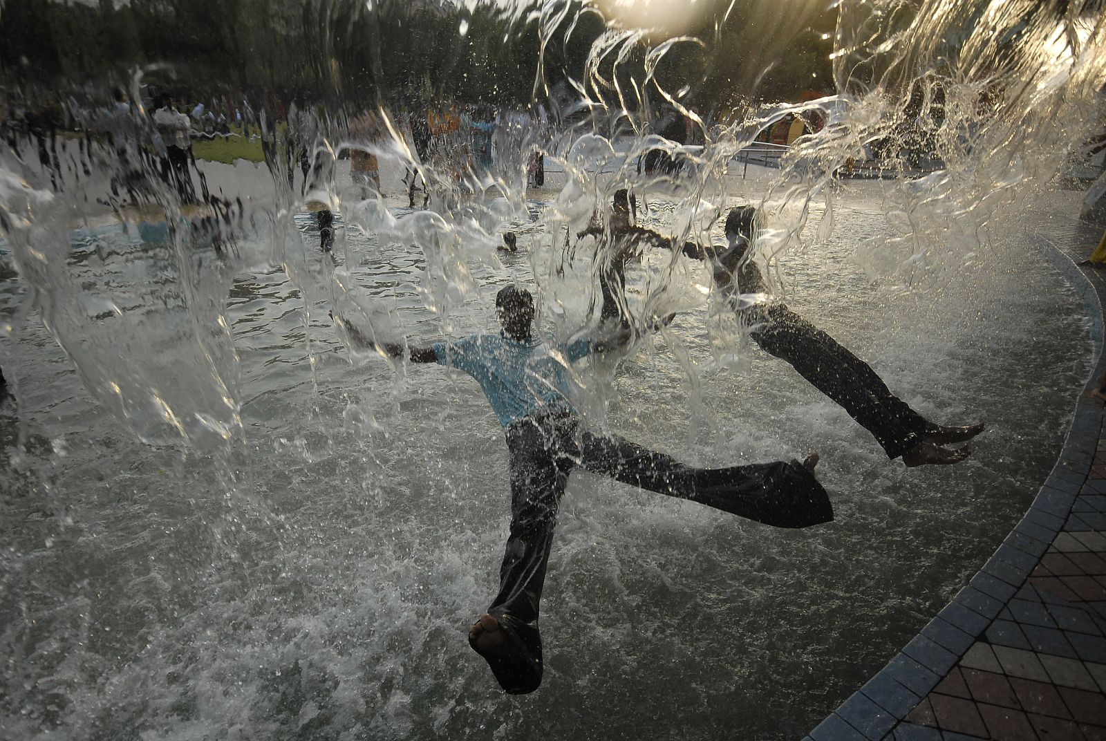 Jóvenes refrescándose en una fuente tras un día de calor agobiante