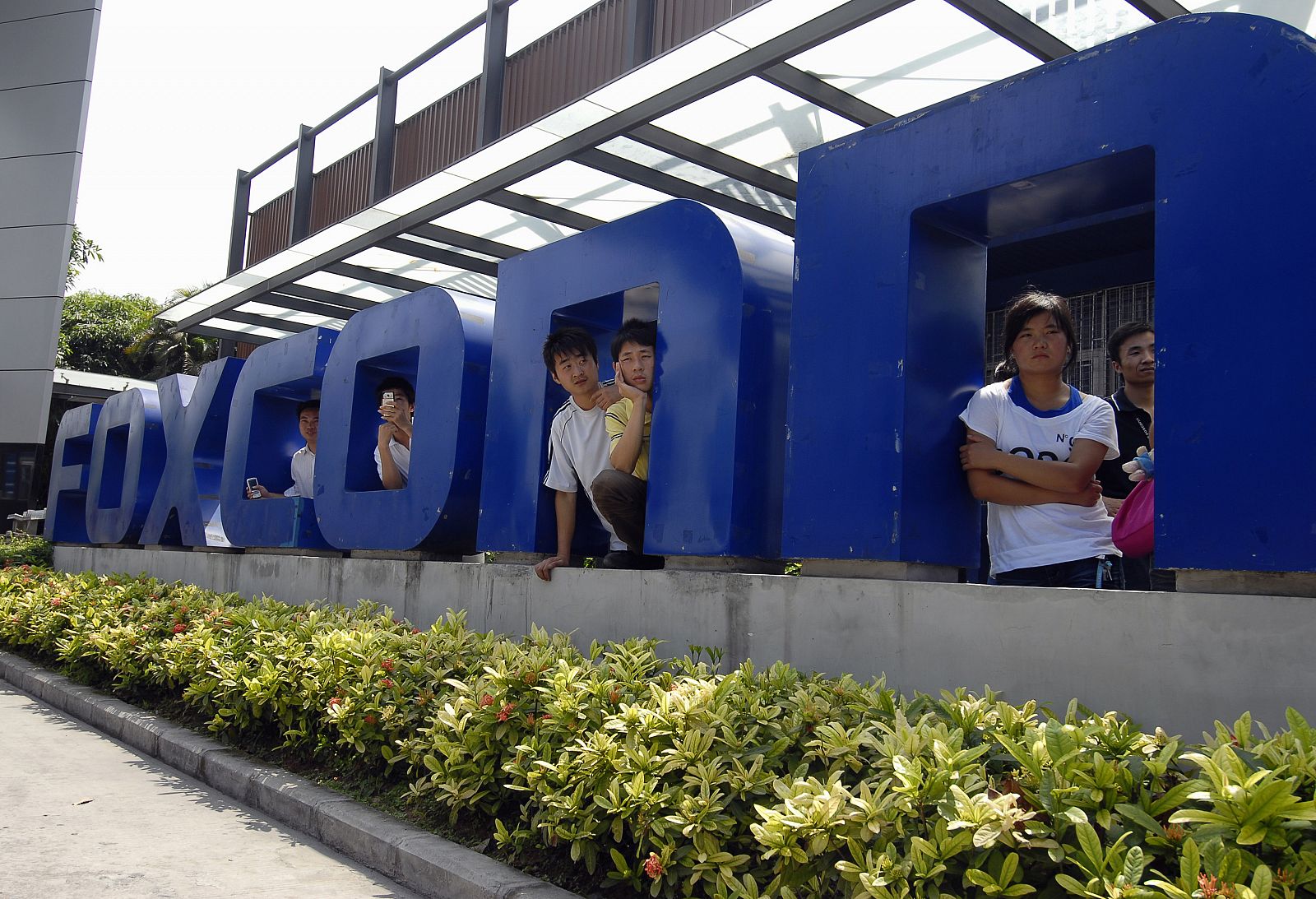 Workers stand at the gate of a Foxconn factory in the township of Longhua in Shenzhen