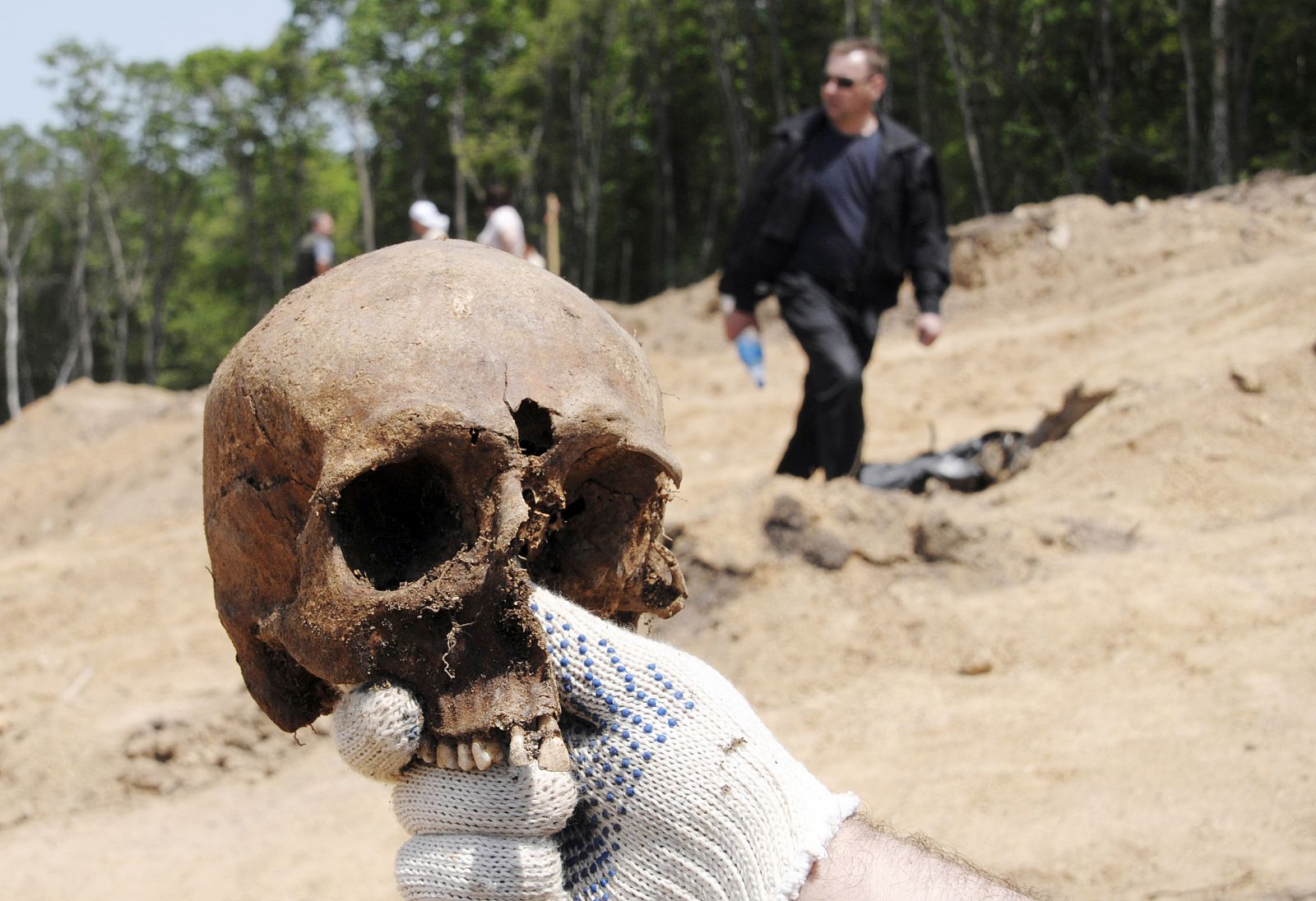 Uno de los investigadores muestra el cráneo encontrado con un agujero de bala