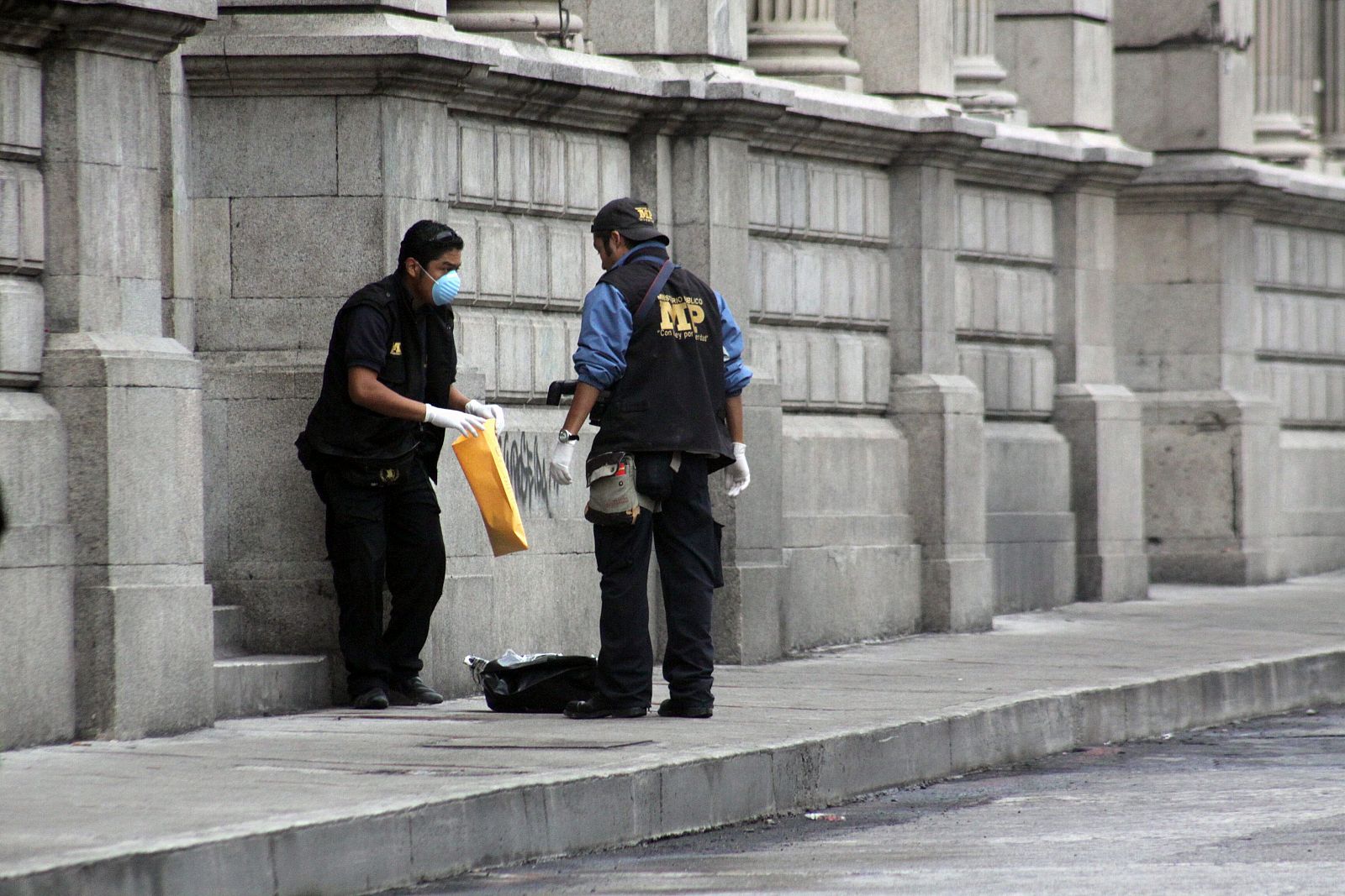 Dos miembros del Ministerio Público recogen evidencias hoy, jueves 10 de junio de 2010, en las afueras de la sede del Congreso de Guatemala, en Ciudad de Guatemala junto a una de las tres cabezas humanas.