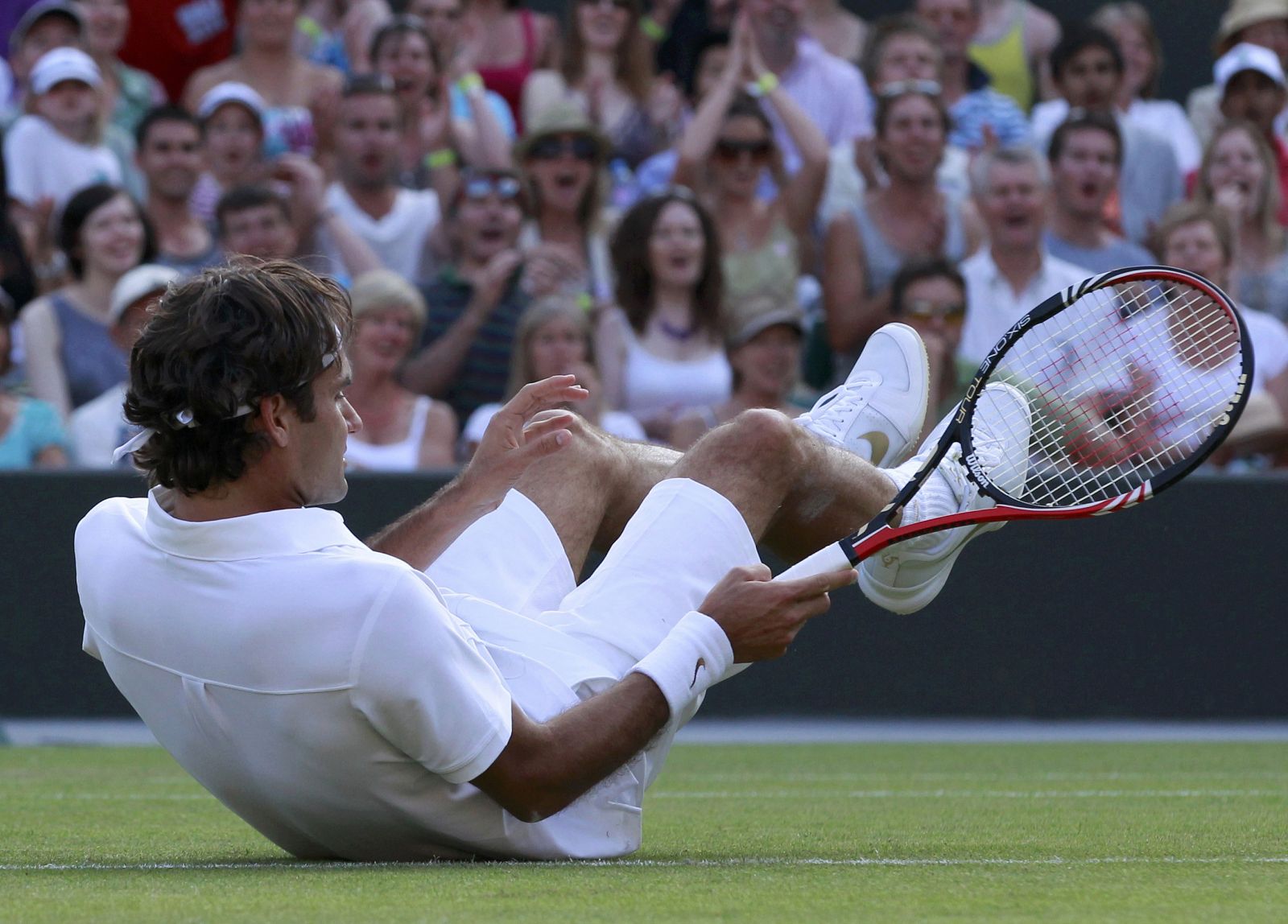 Roger Federer cae al intentar devolver un golpe al serbio Bozoljac.