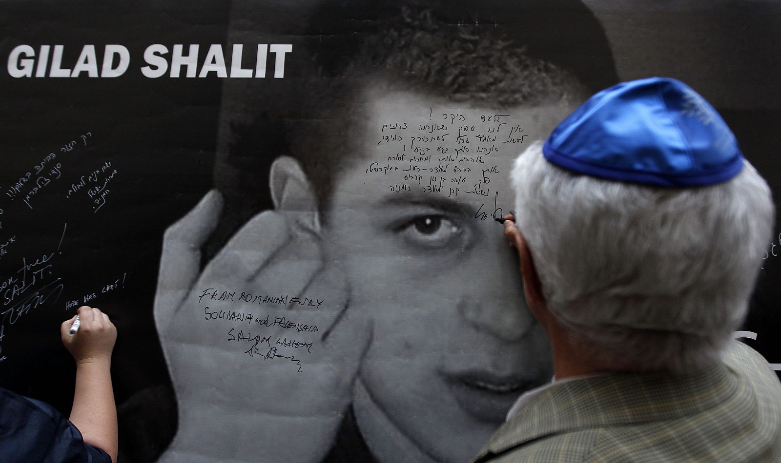 Un miembro de la comunidad israelí escribe un mensaje en un mural para pedir la liberación del soldado Shalit.