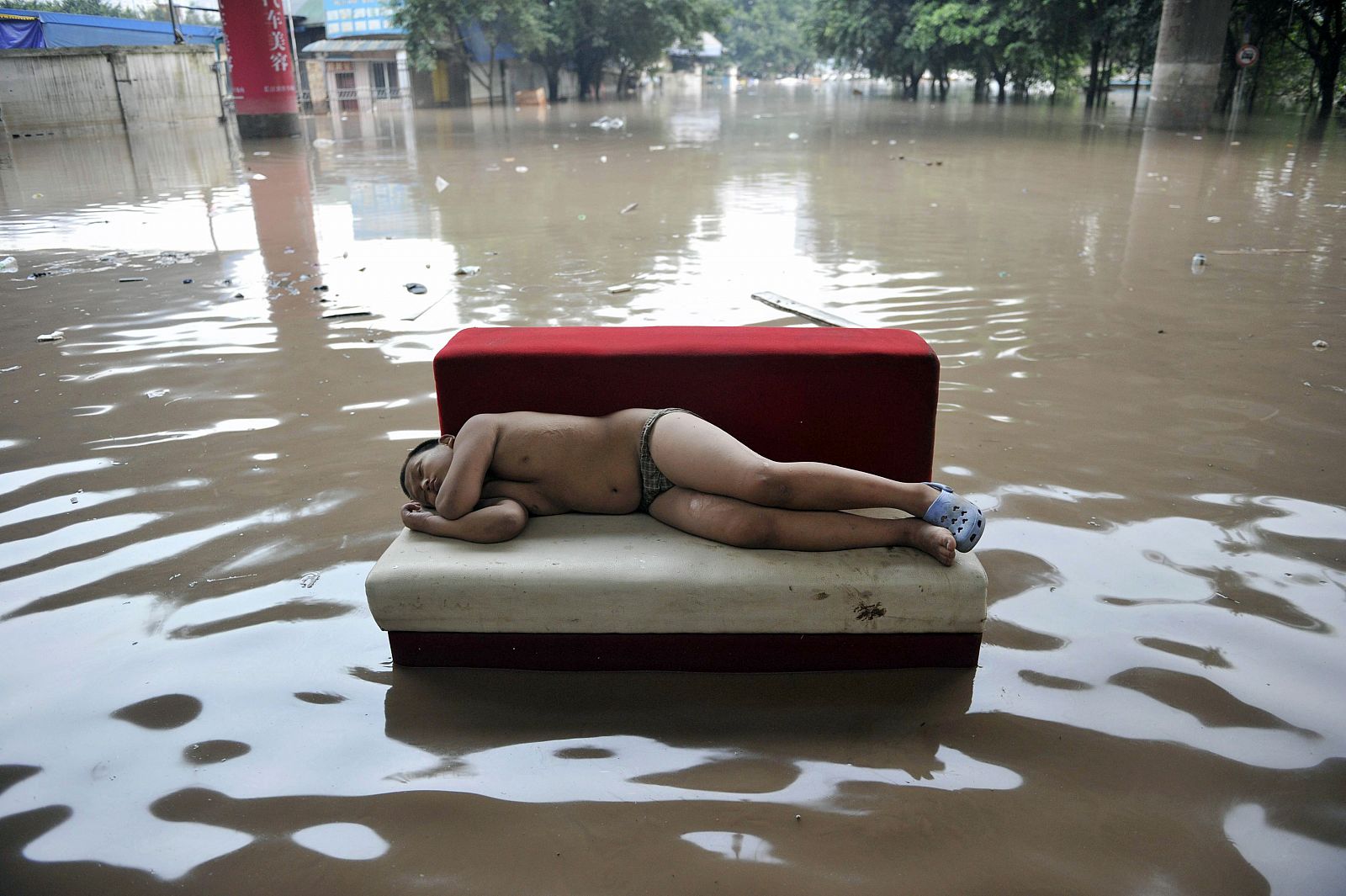 Un niño duerme en un sofá en las calles inundadas del ayuntamiento de Chongqing.