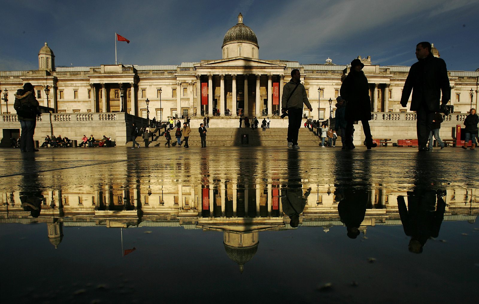 The National Gallery is reflected in surface water in Trafalgar Square in London
