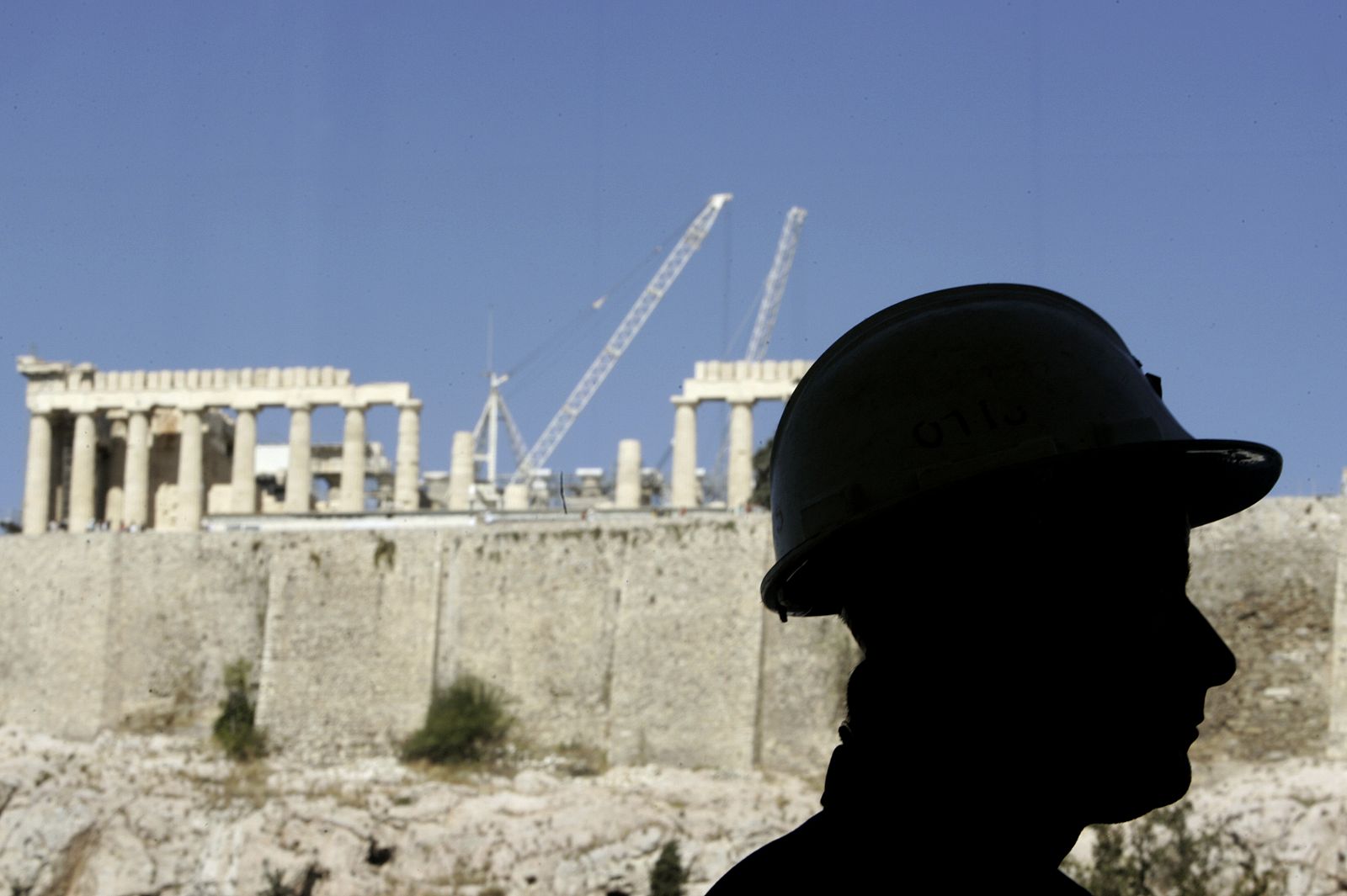 A worker is silhouetted in front of the temple of the Parthenon as he stands inside newly built Acropolis museum in Athens