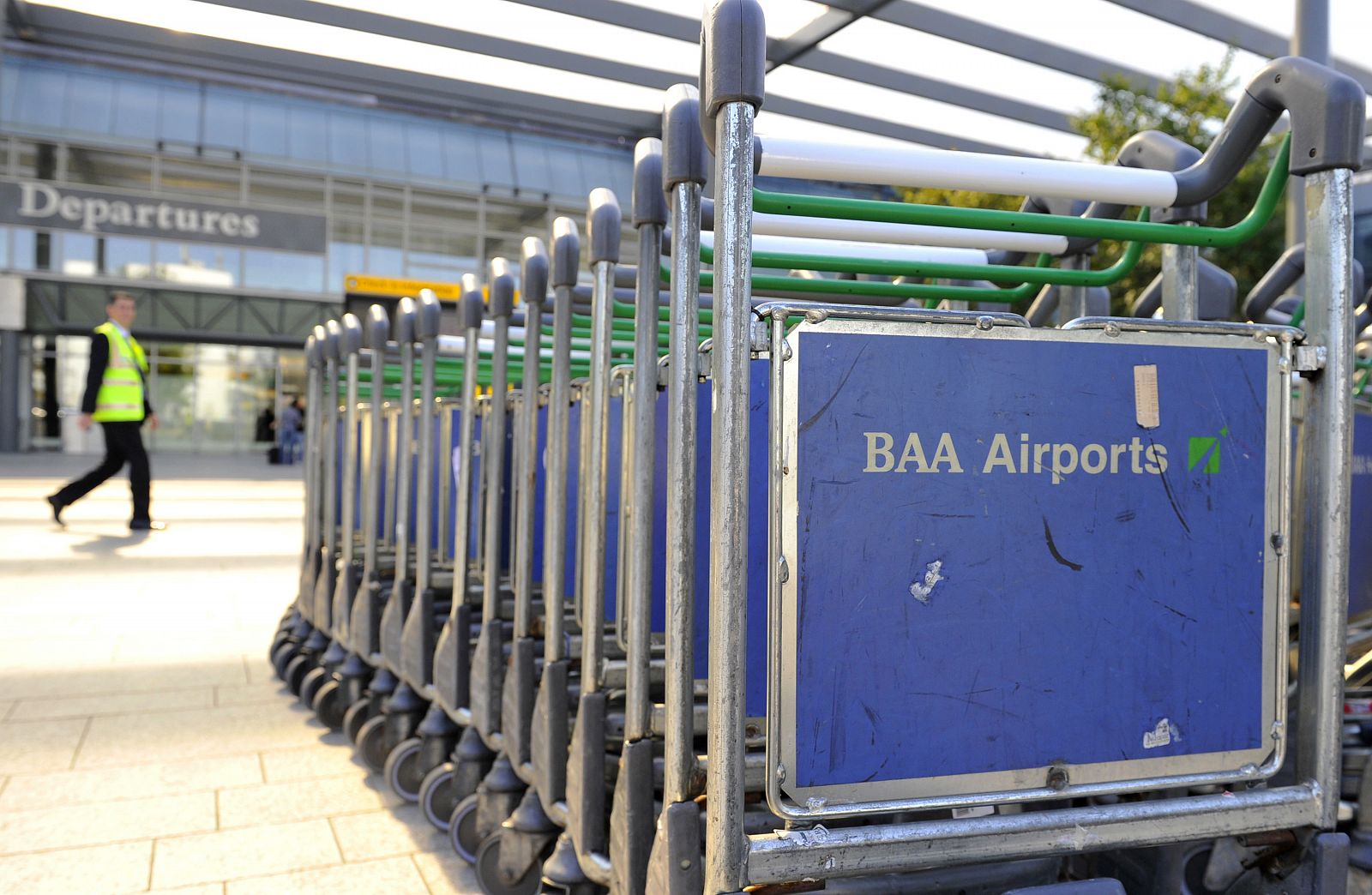 A worker passes luggage trollies at Heathrow Airport in west London