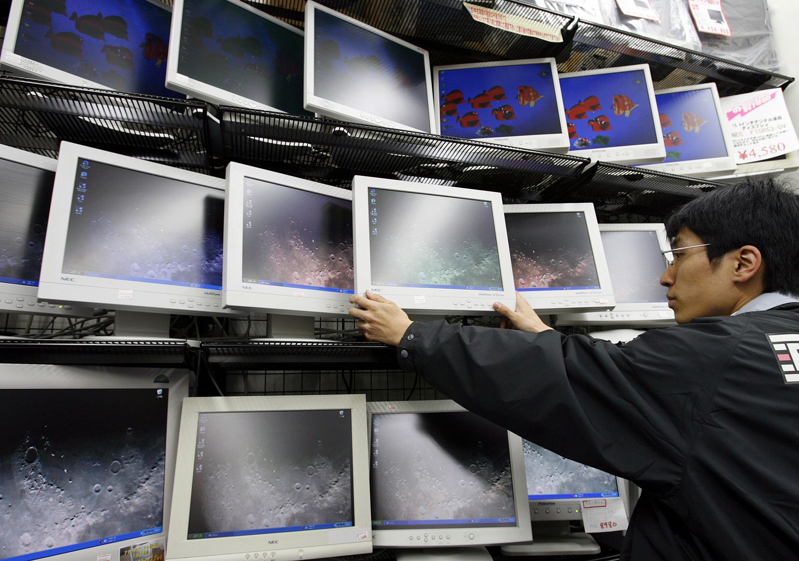 A sales clerk adjusts used liquid crystal displays for computers at a store in Tokyo