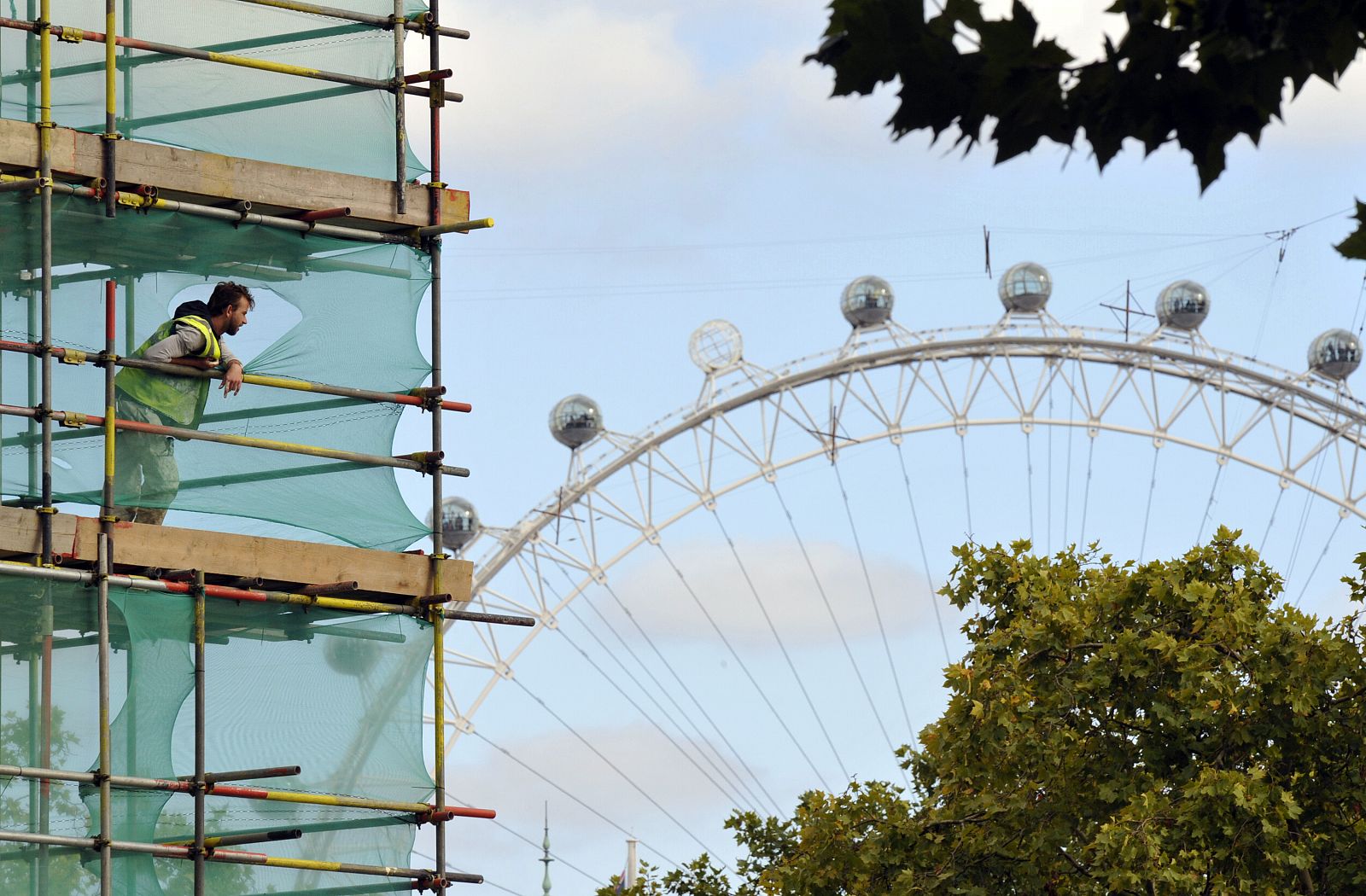 A worker erects scaffolding in central London