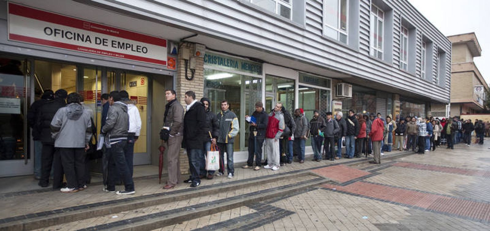 People stand in a queue to enter a government job centre in Madrid
