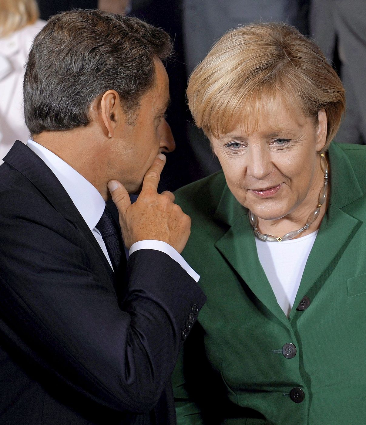 El presidente francés, Nicolás Sarkozy, conversa con la canciller alemana, Ángela Merkel, durante la tensa cumbre europea centrada en la política gala de expulsión de gitanos.