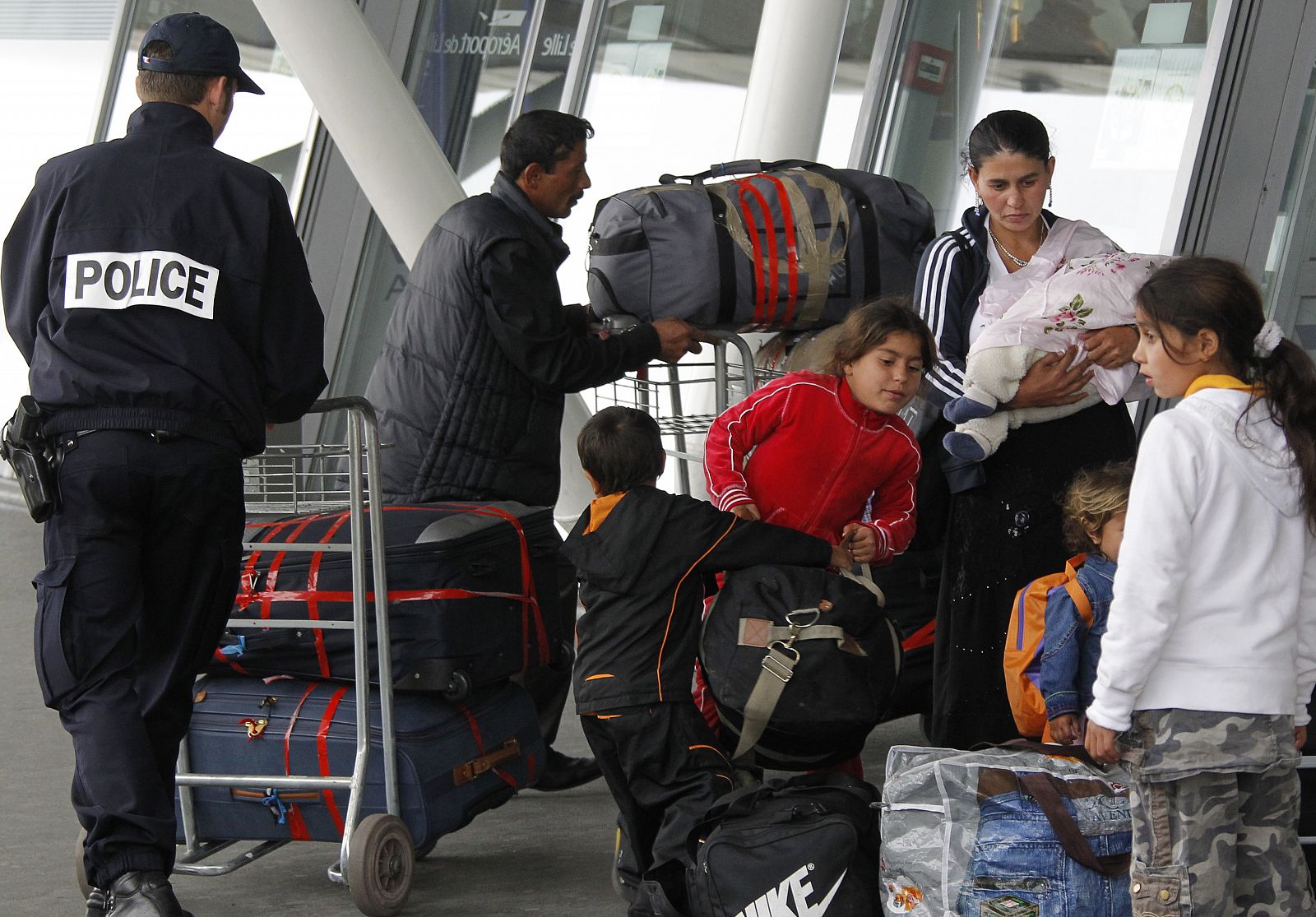 Un policía ayuda a una familia de gitanos que espera a ser deportados a Rumanía.