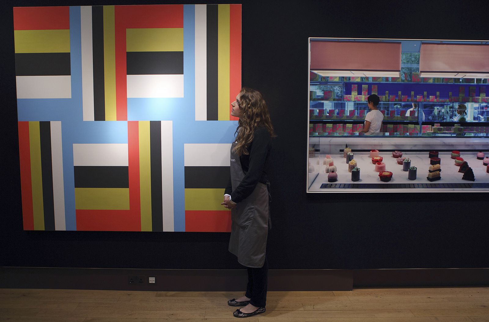 A Christie's employee poses for a photograph with artworks at Christie's in central London
