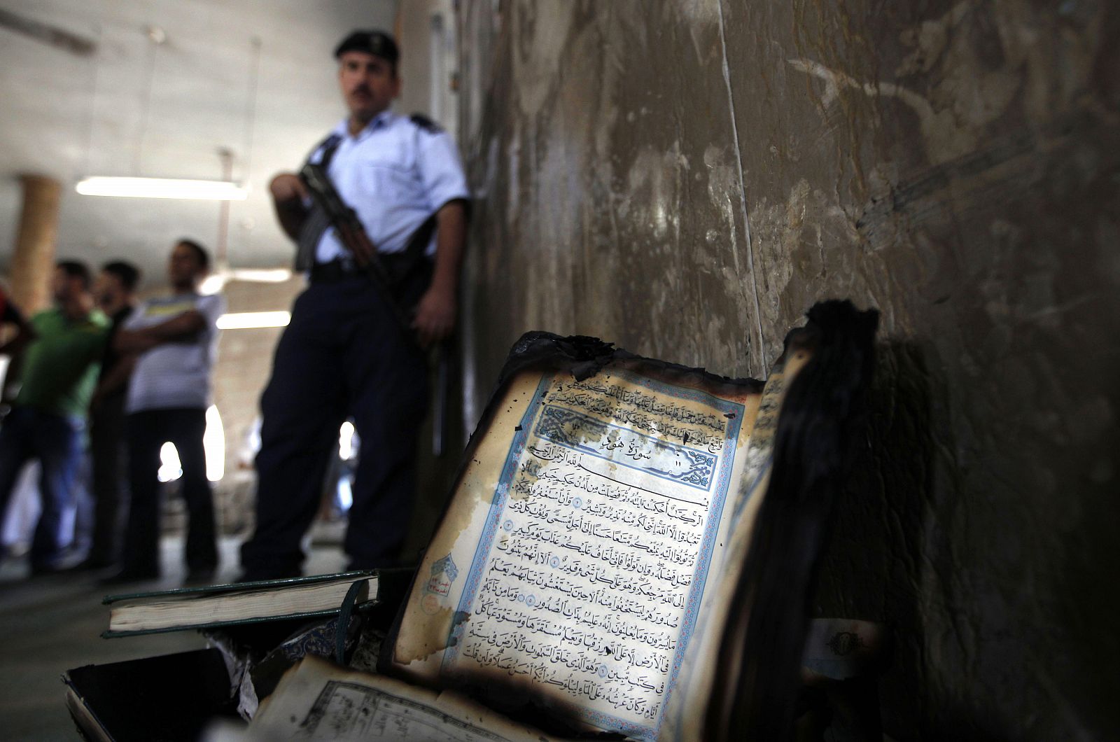 Un Corán parcialmente quemado junto al muro de la mezquita atacada por colonos judíos.