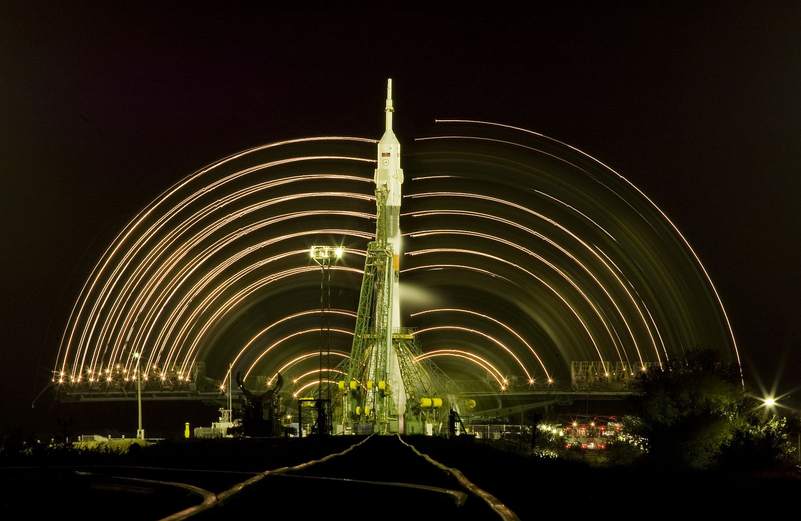 Las  luces de las torres de servicio se mueven alrededor de la nave Soyuz en esta fotografía de larga exposición.