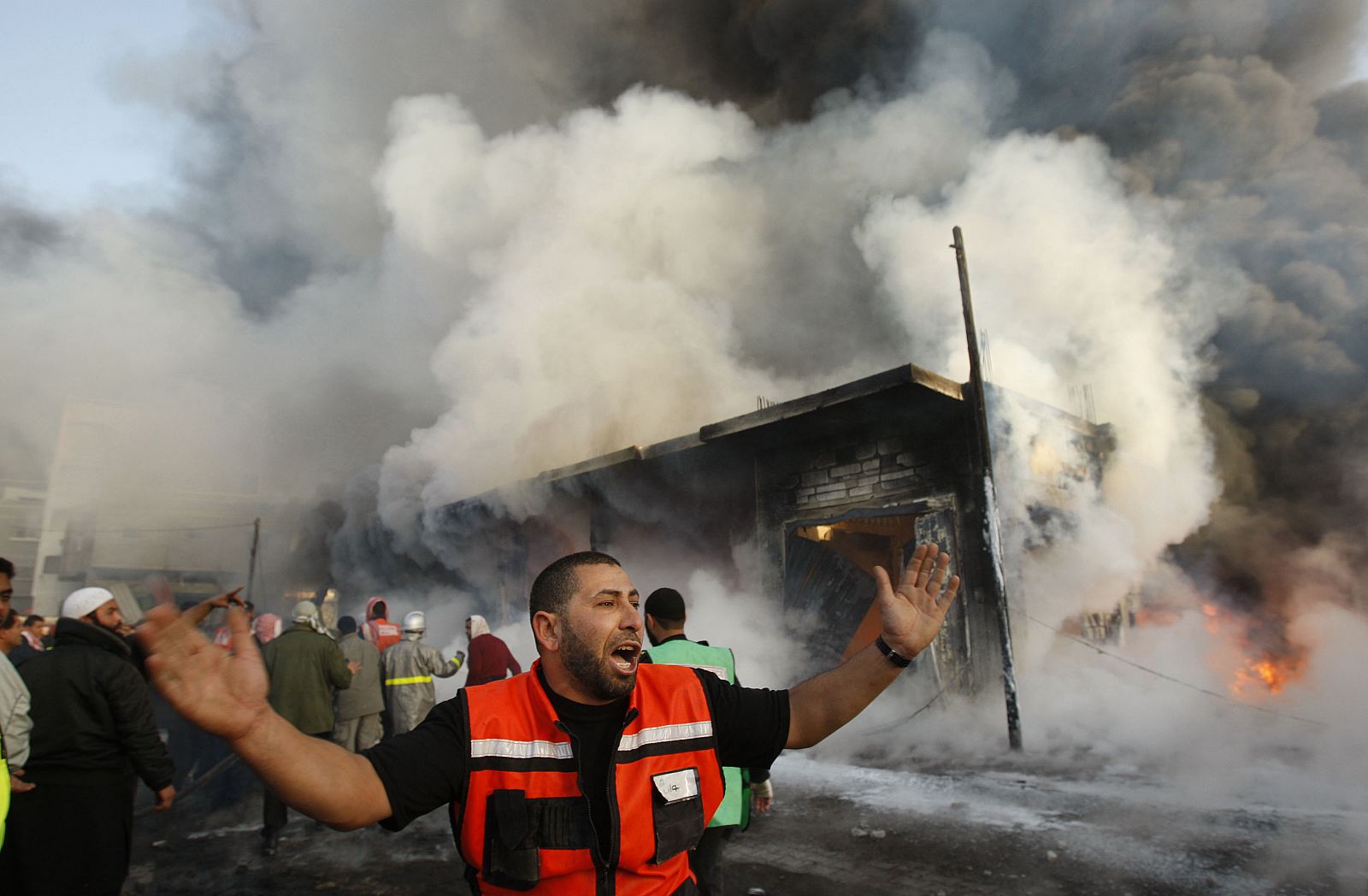 Un bombero palestinos grita frente a un edificio en llamas tras un ataque israelí en la guerra.