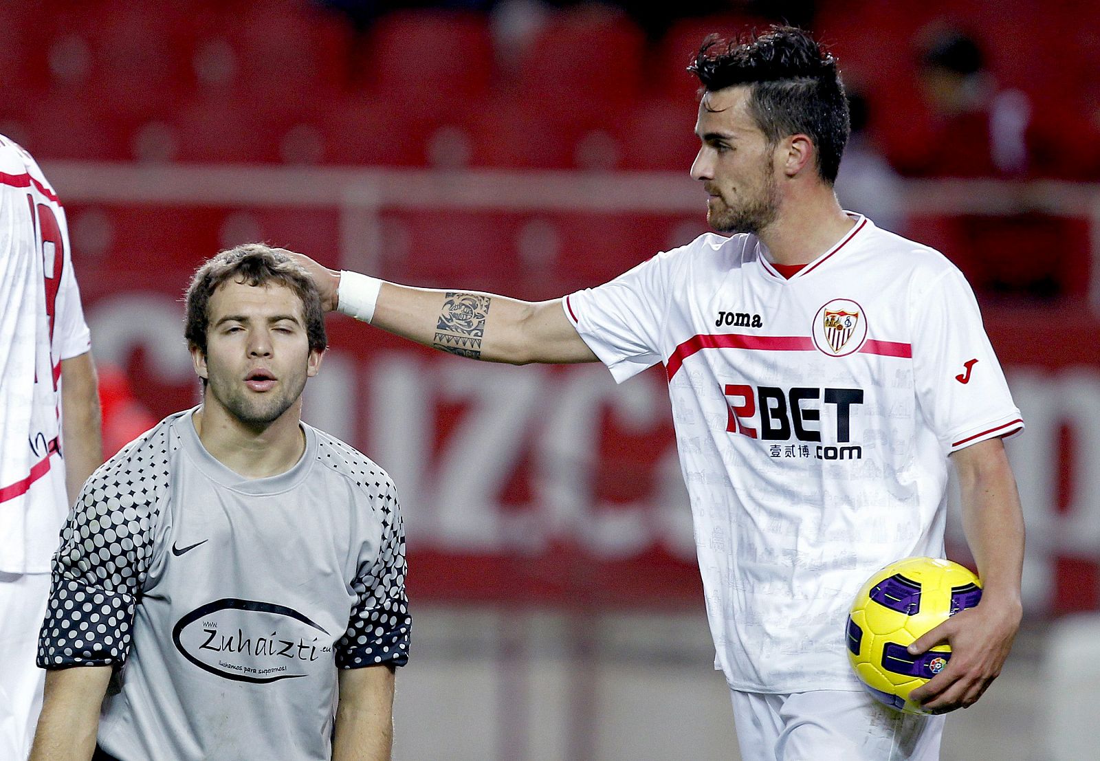 El jugador del Sevilla, Cigarini, consuela al guardameta del Real Unión, San Sebastián, tras marcar el quinto gol del equipo andaluz.