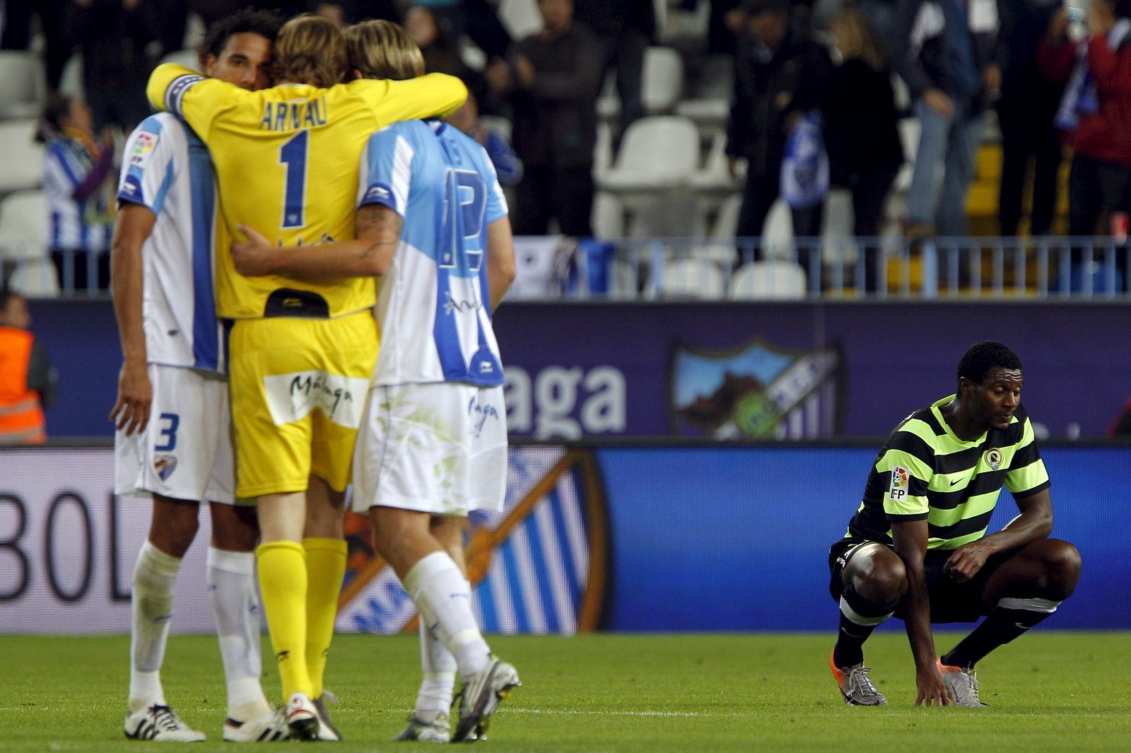 Los jugadores del Málaga, celebran su paso a la siguiente fase de la Copa del Rey, ante el jugador del Hércules C.F, Thomert.
