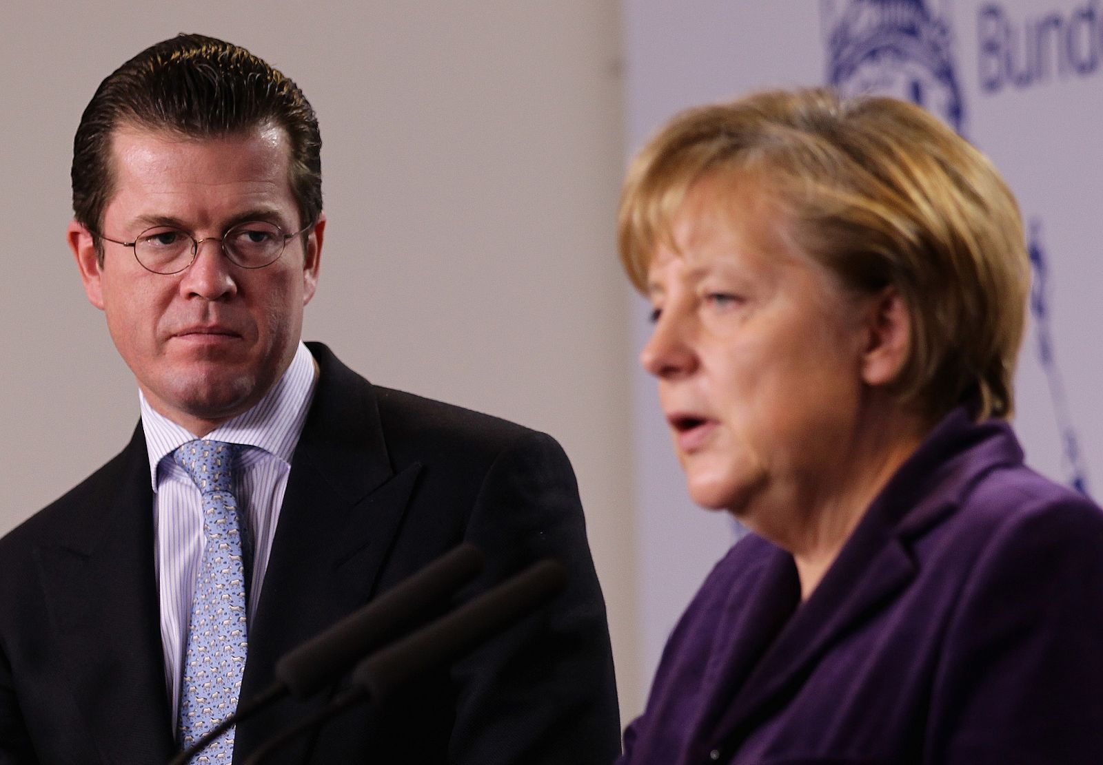 El ministro de Defensa alemán, Karl-Theodor zu Guttenberg observa a la canciller Angel Merkel anunciar las nuevas medidas de reestructuración de Ejército.