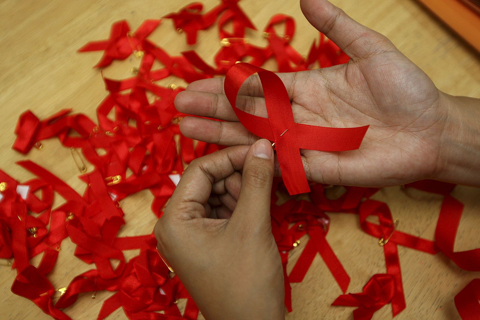 Una joven prepara lazos rojos durante una campaña de concienciación sobre la prevención del contagio del sida