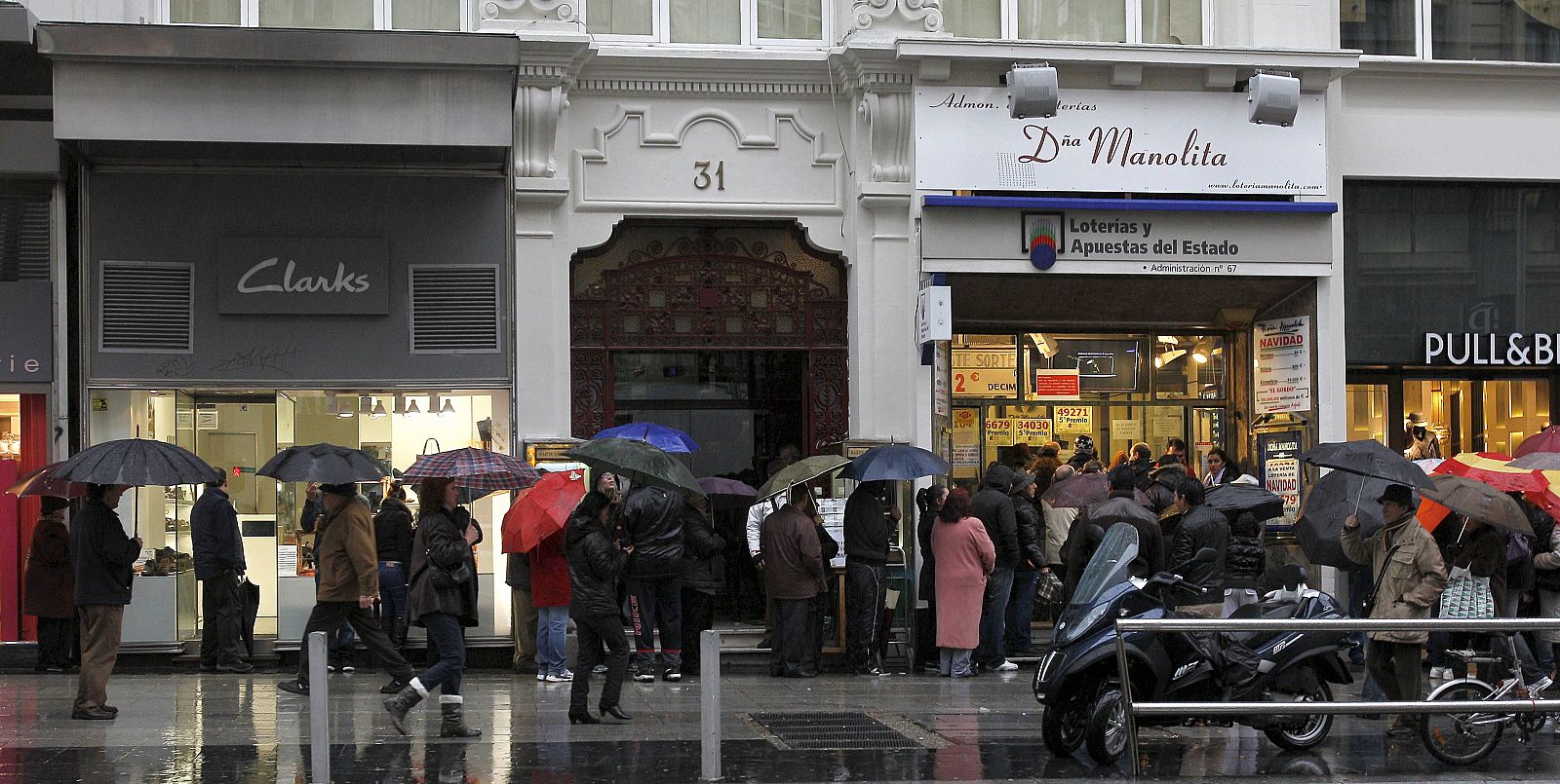 Decenas de personas esperan su turno para comprar lotería en una administración en la Gran Vía de Madrid