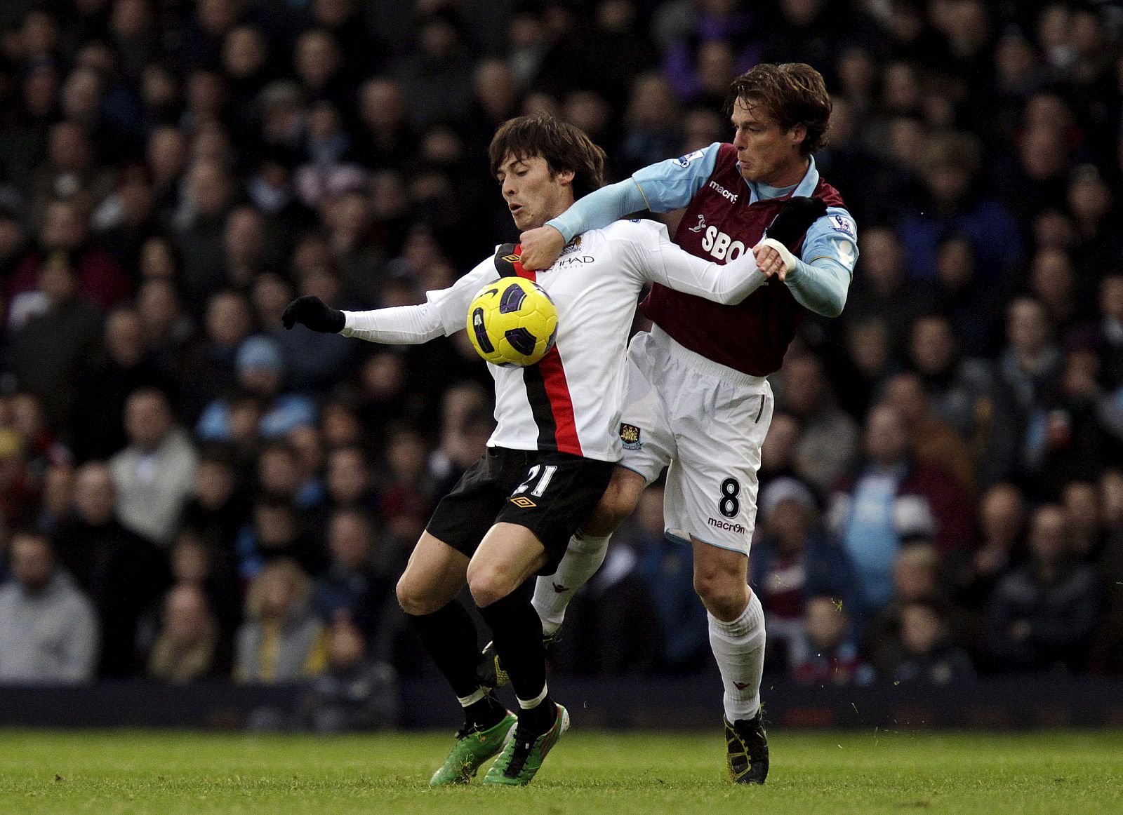 David Silva (i), controla el balón ante Scott Parker (d) del West Ham United
