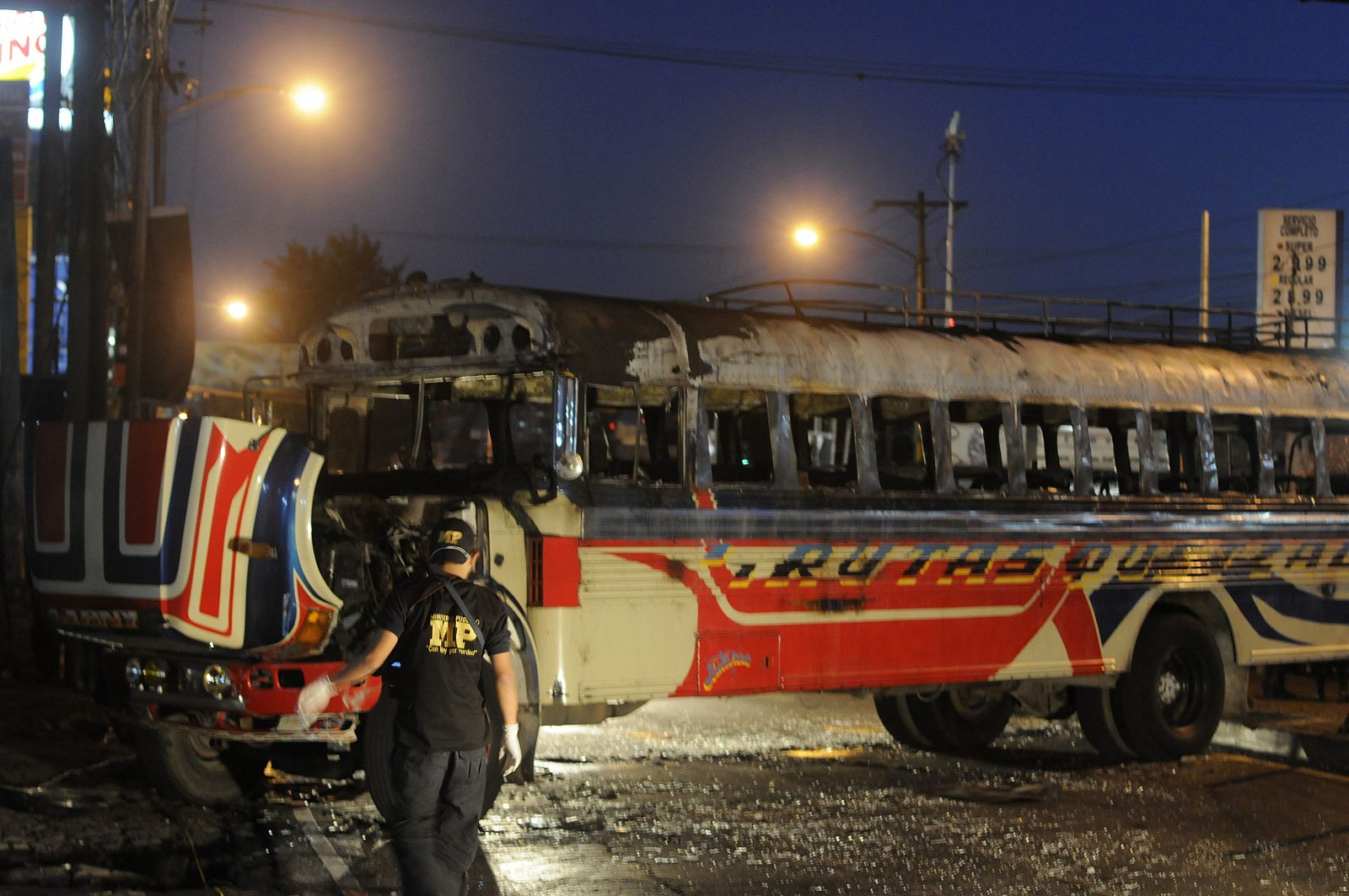 Un fiscal del Ministerio Público inspeccionan el autobús que fue impactado por una bomba lanzada por desconocidos