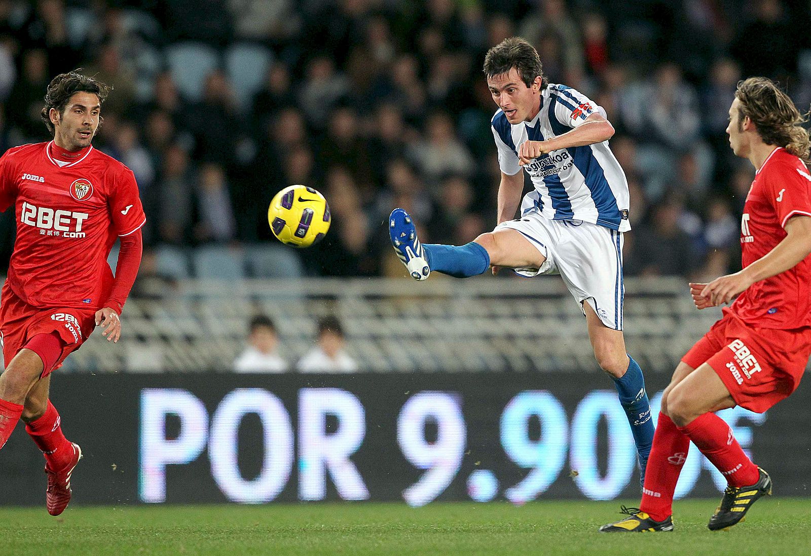 Joseba Llorente (c), golpea el balón ante los defensores del Sevilla, Escudé (i) y Alexis