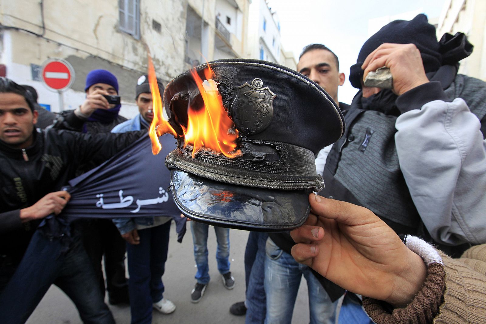 Manifestantes queman un gorro de Policía durante los choques en Túnez.