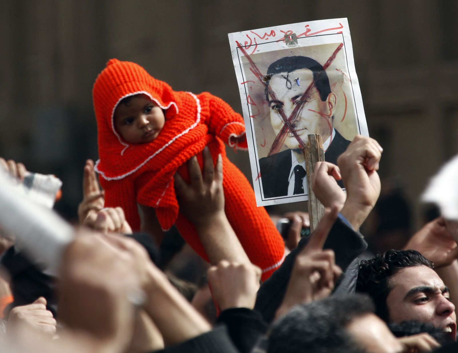 A protester holds up a child in front of a picture of Egypt's President Hosni Mubarak during a protest in Cairo