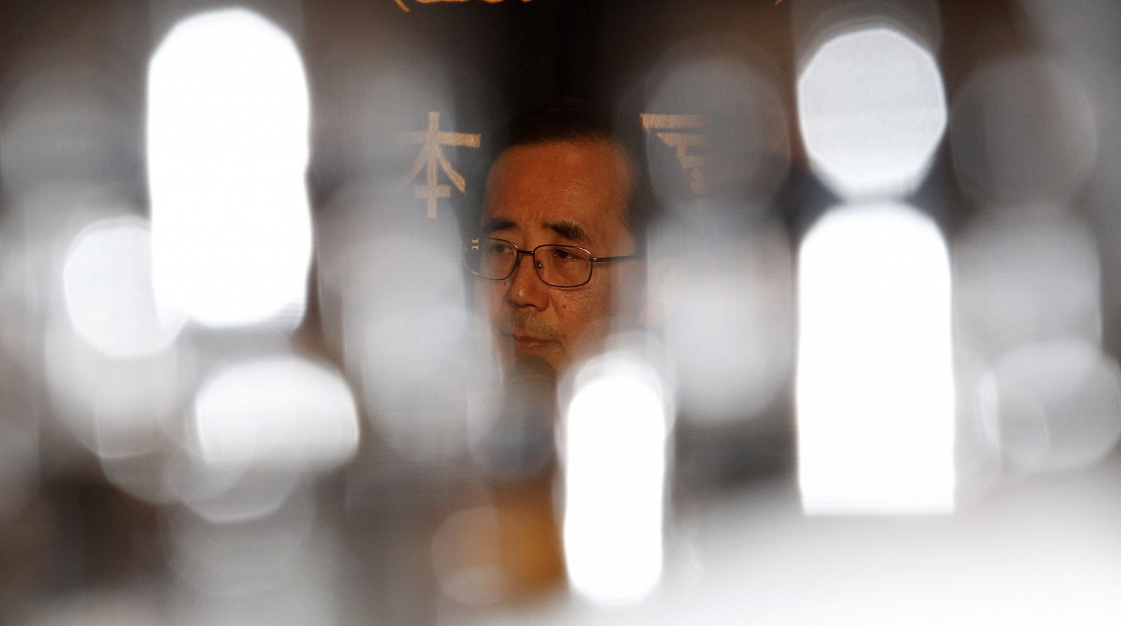 Bank of Japan Governor Masaaki Shirakawa is seen through reflections on glasses during a news conference in Tokyo