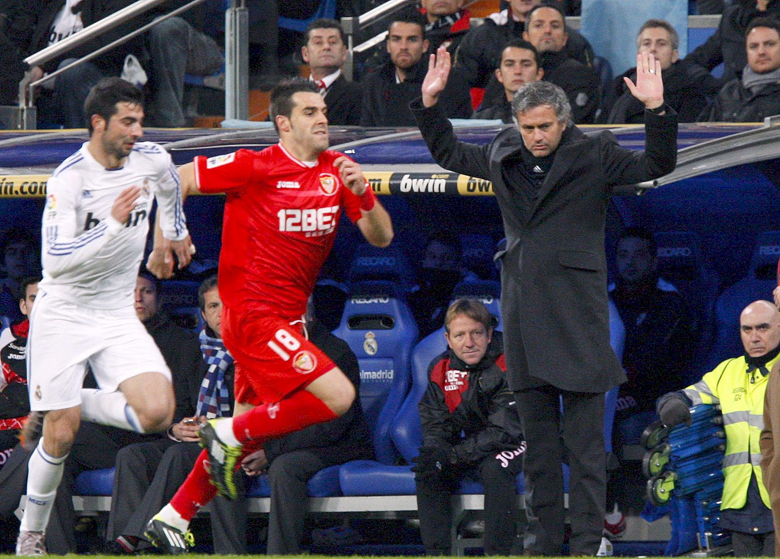 El madridista Albiol corre con el sevillista Negredo ante la mirada de Mourinho.