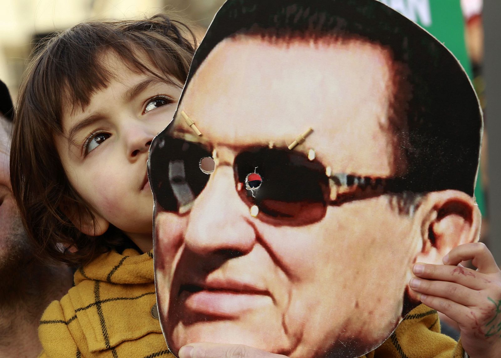 Una niña sostiene una máscara del expresidente Hosni Mubarak